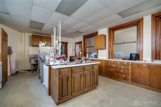 531 W Ash St, Piqua, OH 45356 - kitchen with light countertops, brown cabinetry, light colored carpet, a drop ceiling, and a center island with sink