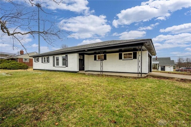 back of house with a garage, brick siding, and a yard