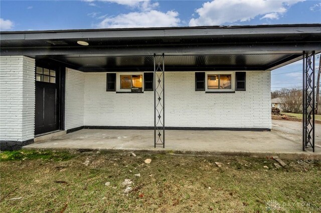 back of house featuring an attached carport and brick siding
