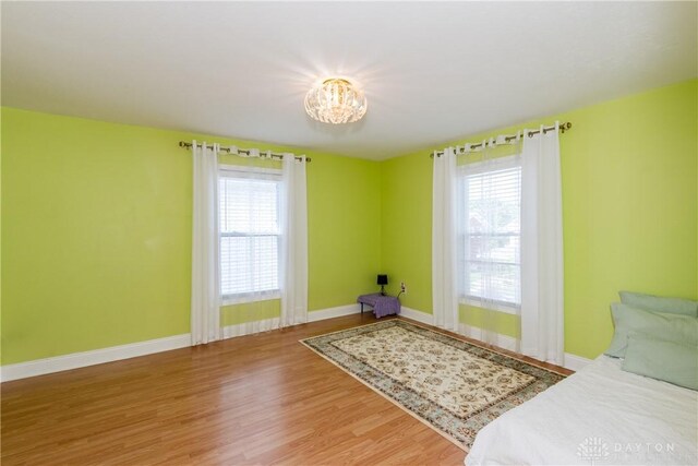 82 Notre Dame Ave, Dayton, OH 45404 - unfurnished bedroom with multiple windows, wood finished floors, baseboards, and a chandelier