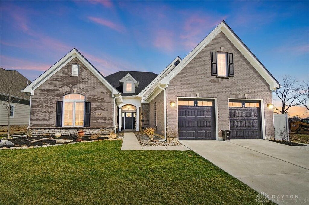 traditional home with brick siding, driveway, and a lawn