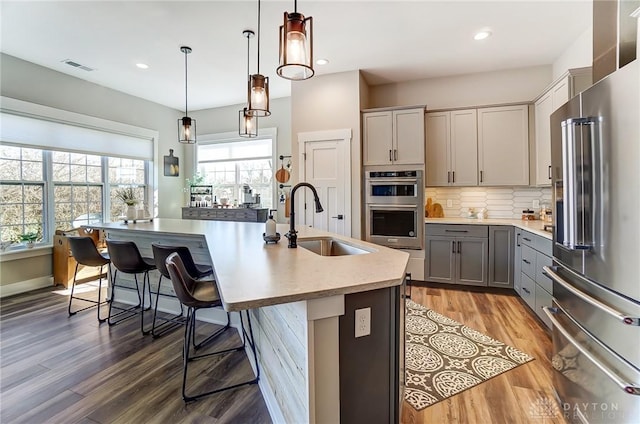 703 Doral Ct, Dayton, OH 45458 - kitchen with stainless steel appliances, gray cabinets, light wood finished floors, a breakfast bar, and light countertops