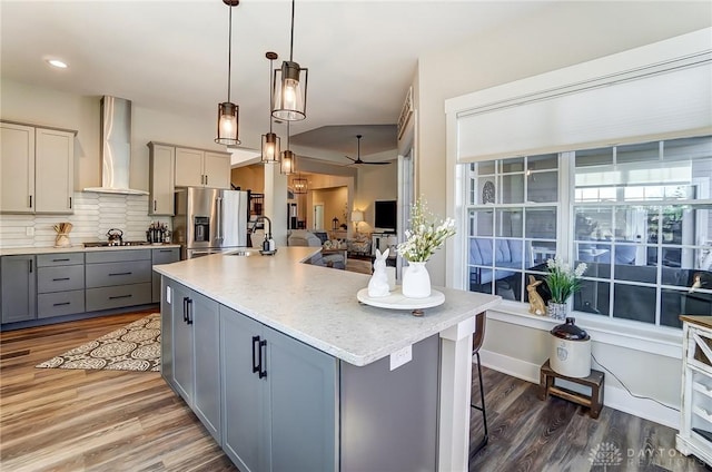 703 Doral Ct, Dayton, OH 45458 - kitchen featuring gray cabinetry, appliances with stainless steel finishes, wall chimney range hood, wood finished floors, and tasteful backsplash