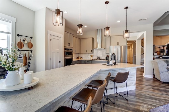 703 Doral Ct, Dayton, OH 45458 - kitchen featuring wall chimney exhaust hood, appliances with stainless steel finishes, dark wood-style floors, a breakfast bar area, and recessed lighting