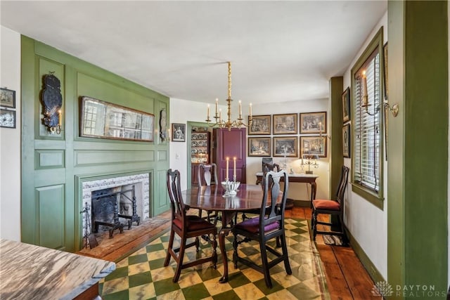 dining area featuring a fireplace with flush hearth, baseboards, and a chandelier