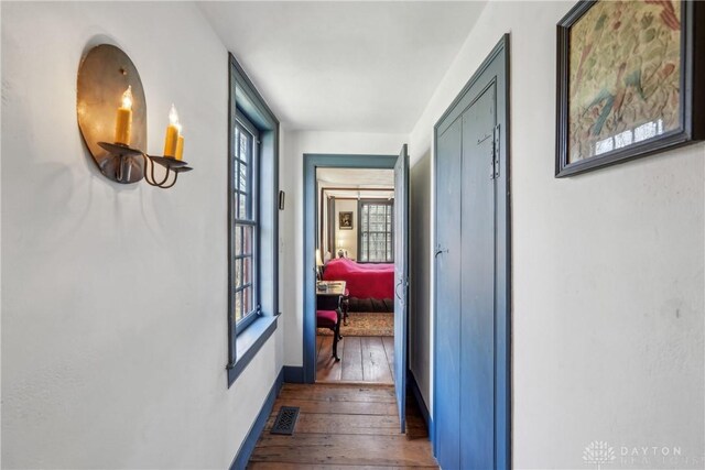 corridor with baseboards, dark wood-style floors, and visible vents