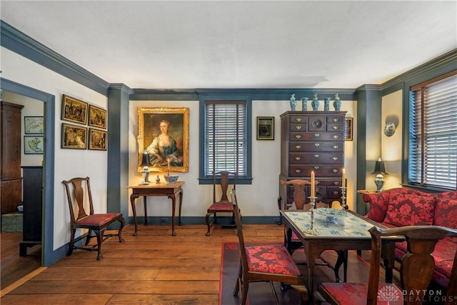 living area with baseboards, crown molding, and wood finished floors