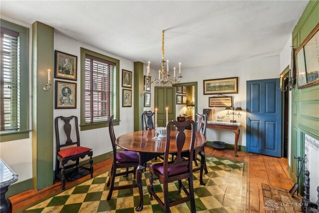dining space featuring baseboards, a chandelier, and wood finished floors