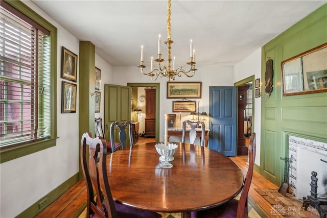 dining room featuring a wealth of natural light, a notable chandelier, wood finished floors, and a decorative wall