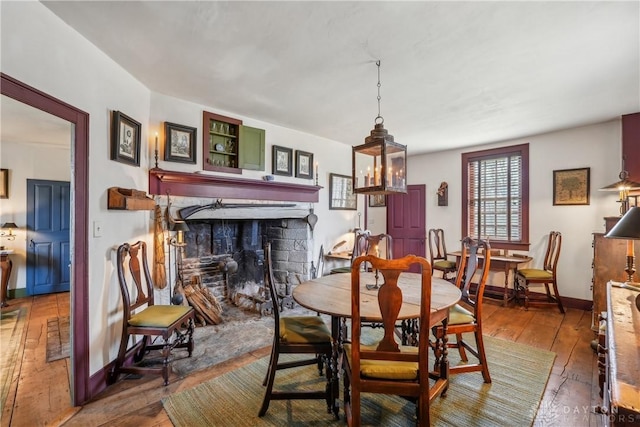 dining space featuring baseboards, a fireplace, and wood-type flooring
