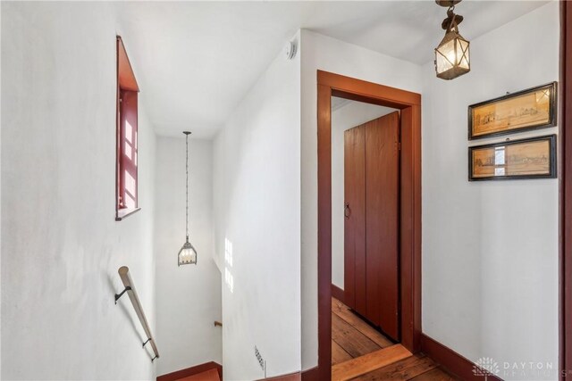 corridor featuring an upstairs landing and wood finished floors