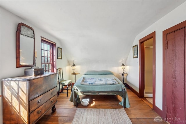 bedroom with hardwood / wood-style floors, baseboards, and vaulted ceiling