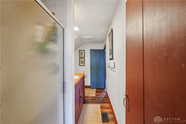 corridor with wood finished floors, baseboards, and visible vents