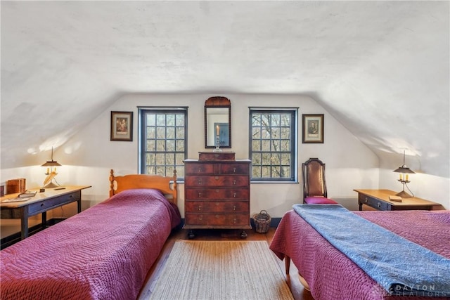 bedroom featuring wood finished floors, vaulted ceiling, and multiple windows