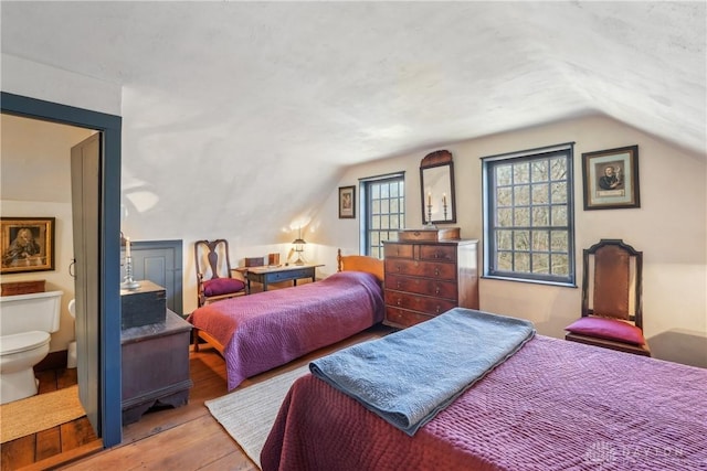 bedroom with vaulted ceiling and wood finished floors