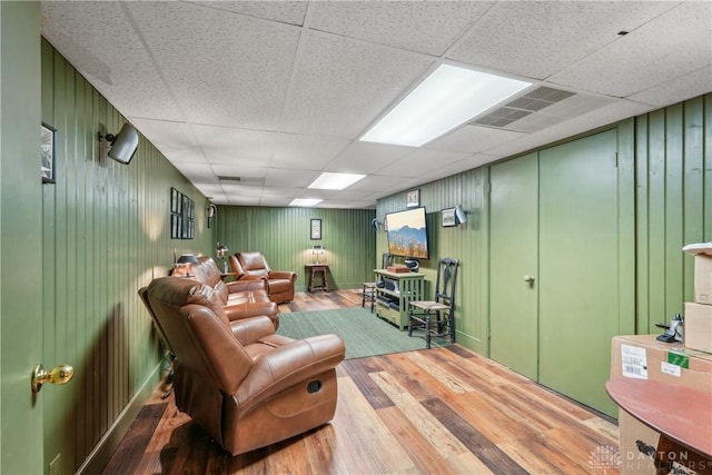 living area with a paneled ceiling, visible vents, and wood finished floors