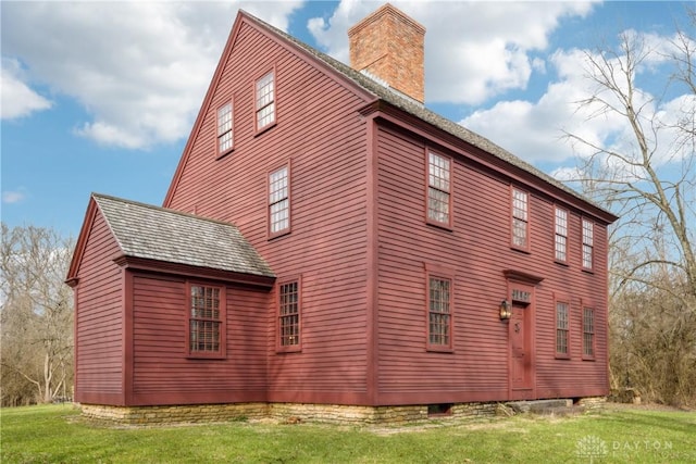 view of property exterior with a chimney and a yard