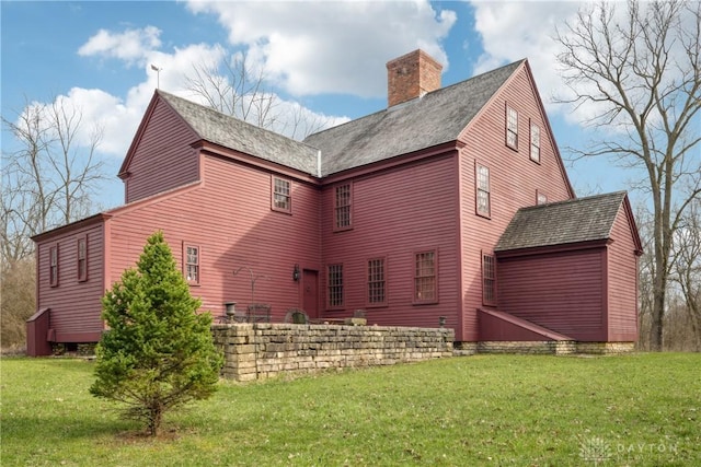 back of house with a chimney and a yard