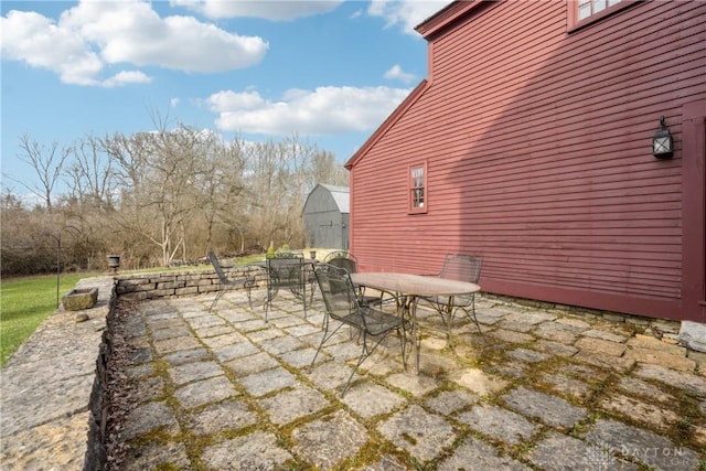 view of patio / terrace featuring an outbuilding, a shed, and outdoor dining space