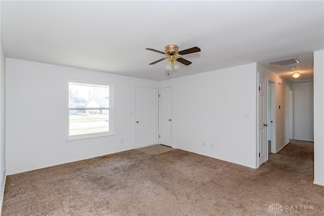 unfurnished room featuring visible vents, carpet floors, and a ceiling fan