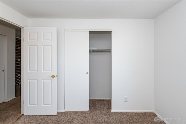 unfurnished bedroom with carpet, a closet, and baseboards
