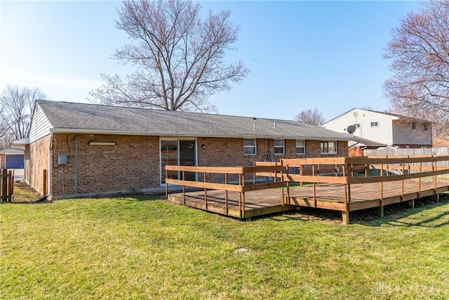 back of house featuring brick siding, a wooden deck, and a yard