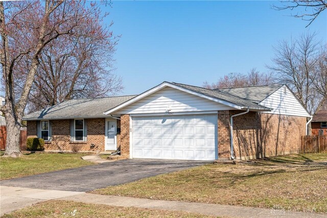 ranch-style home featuring driveway, a front yard, fence, brick siding, and a garage