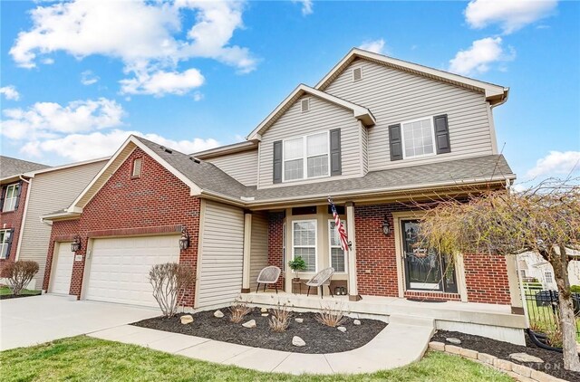 traditional home with driveway, covered porch, roof with shingles, brick siding, and a garage