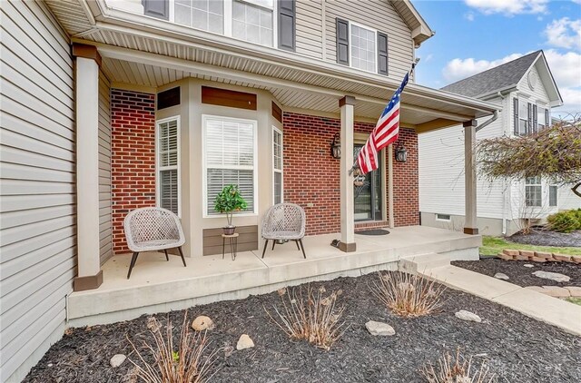 doorway to property with covered porch and brick siding