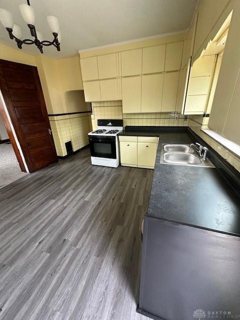 324 Warren St, Dayton, OH 45402 - kitchen featuring gas range gas stove, a sink, dark countertops, dark wood finished floors, and a chandelier