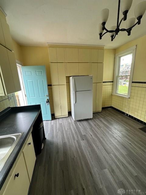 324 Warren St, Dayton, OH 45402 - kitchen with freestanding refrigerator, dark wood-style flooring, dark countertops, a chandelier, and a wainscoted wall