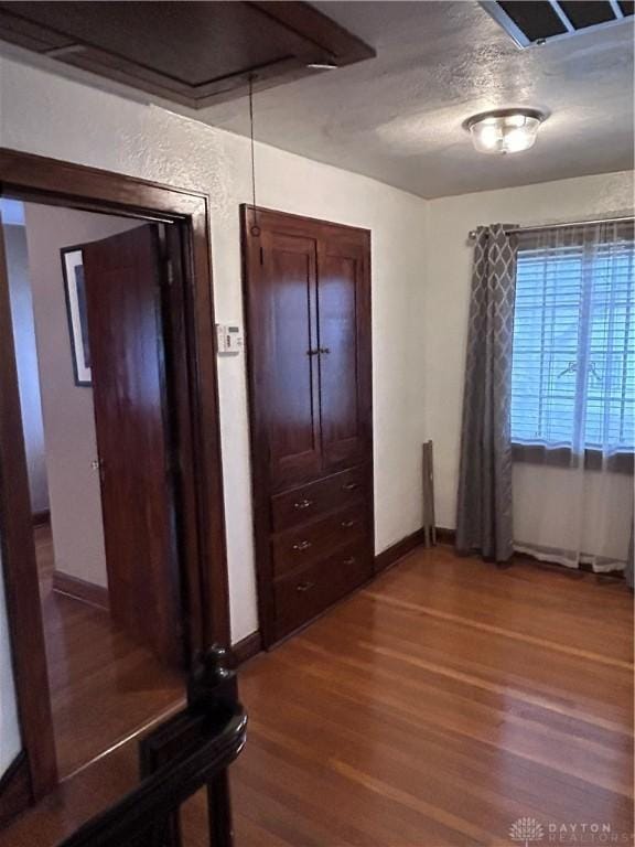 unfurnished bedroom featuring visible vents, a textured ceiling, baseboards, and wood finished floors