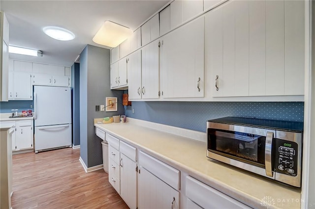 127 W Woodbury Dr, Dayton, OH 45415 - kitchen featuring white cabinets, light countertops, freestanding refrigerator, and stainless steel microwave