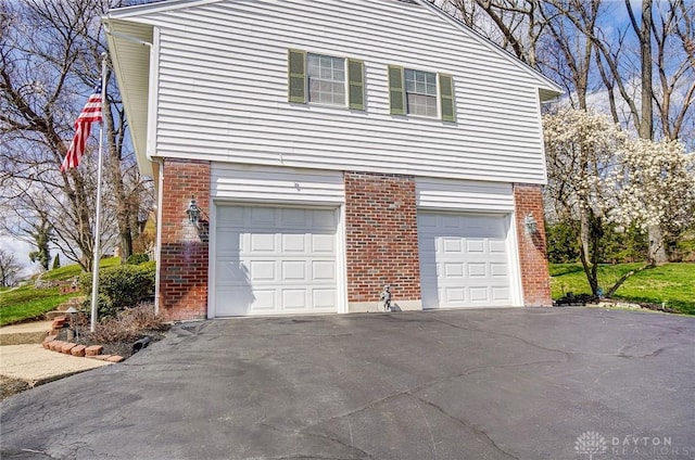 127 W Woodbury Dr, Dayton, OH 45415 - view of side of home featuring brick siding, driveway, and a garage