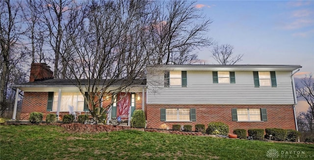 127 W Woodbury Dr, Dayton, OH 45415 - split level home featuring a front lawn, brick siding, and a chimney