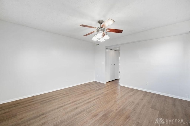 spare room featuring wood finished floors, ceiling fan, baseboards, and visible vents