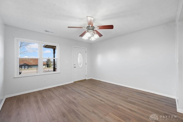 foyer with baseboards, a textured ceiling, visible vents, ceiling fan, and wood finished floors
