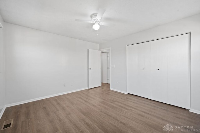 unfurnished bedroom featuring visible vents, baseboards, a closet, and wood finished floors