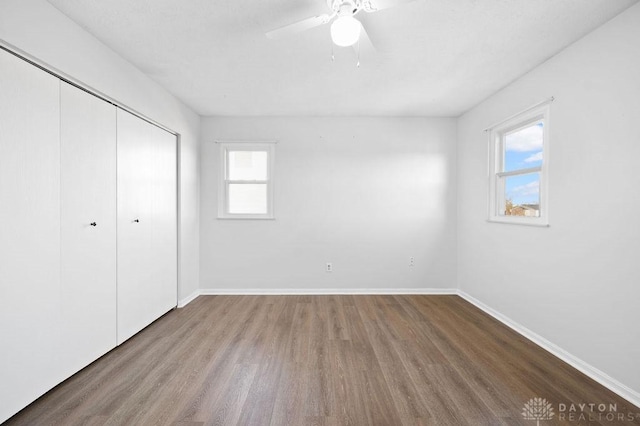 unfurnished bedroom featuring a closet, baseboards, a ceiling fan, and wood finished floors