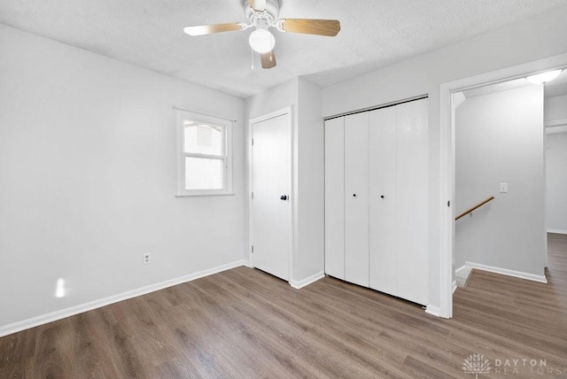 unfurnished bedroom with ceiling fan, baseboards, a textured ceiling, and wood finished floors