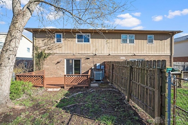 rear view of house featuring brick siding, a deck, central AC, and fence