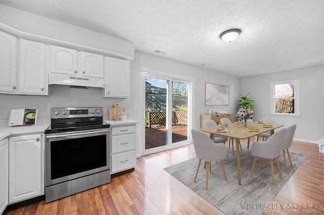 kitchen with a textured ceiling, white cabinets, under cabinet range hood, light countertops, and stainless steel electric range