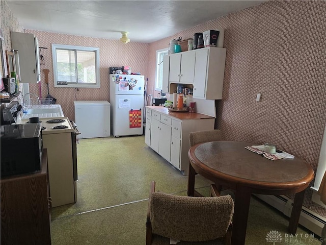 207 E Main St, New Paris, OH 45347 - kitchen with white appliances, wallpapered walls, white cabinetry, and a baseboard heating unit