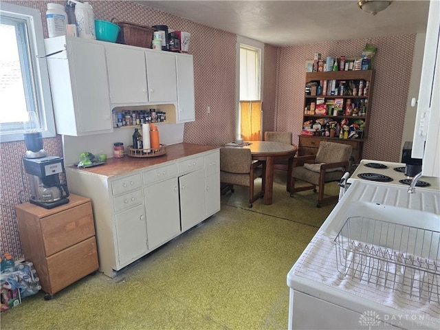 207 E Main St, New Paris, OH 45347 - kitchen with wallpapered walls, white cabinetry, light countertops, and white electric range oven