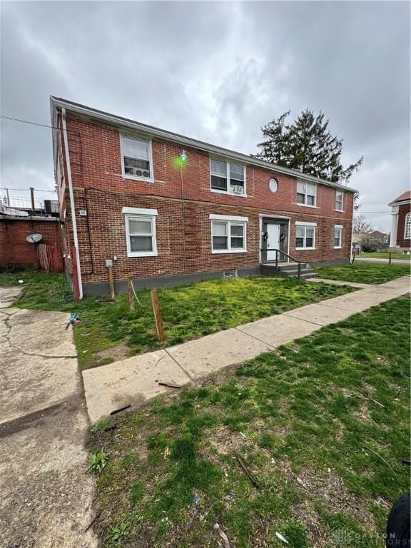 townhome / multi-family property with a front yard and brick siding