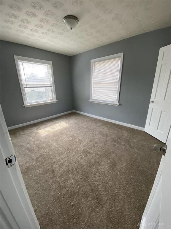 carpeted spare room with baseboards and a textured ceiling