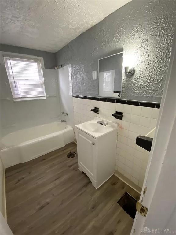 bathroom with wood finished floors, a textured wall, and a textured ceiling