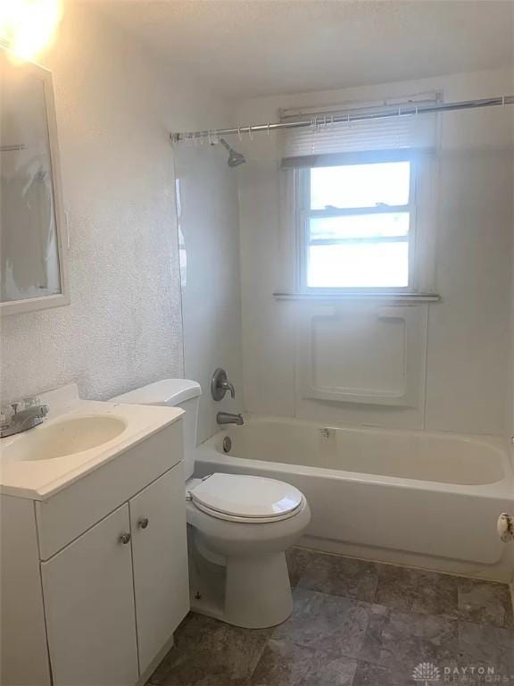 bathroom with toilet, vanity, a textured wall, and washtub / shower combination