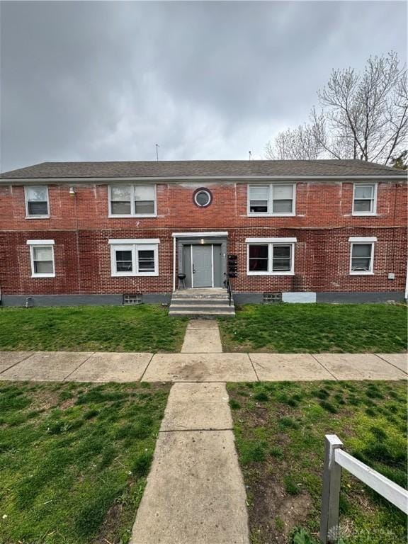view of front facade with brick siding and a front lawn