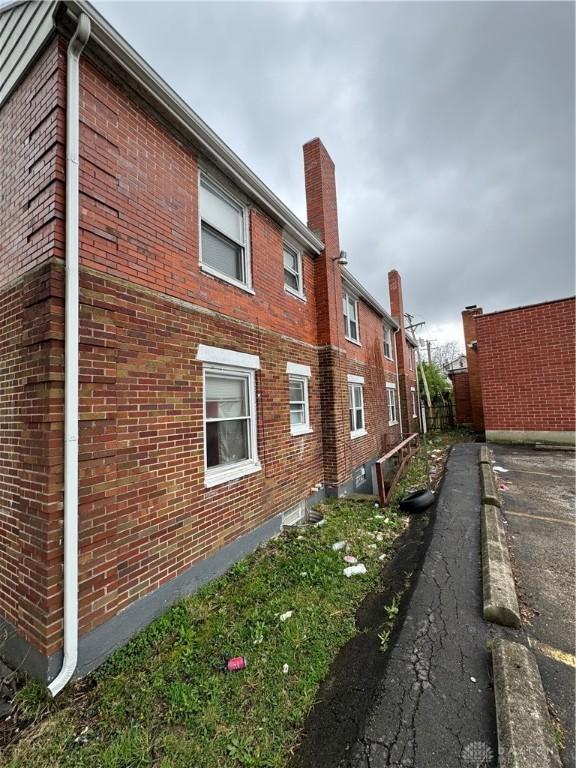 view of side of home featuring brick siding and a chimney